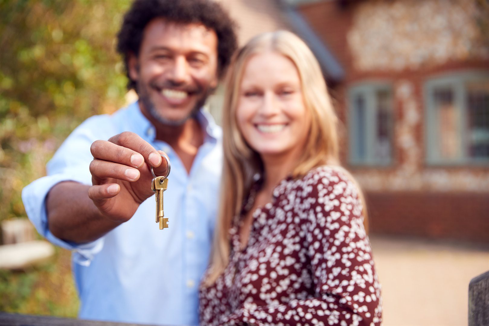 portrait-of-excited-couple-by-gate-holding-house-key